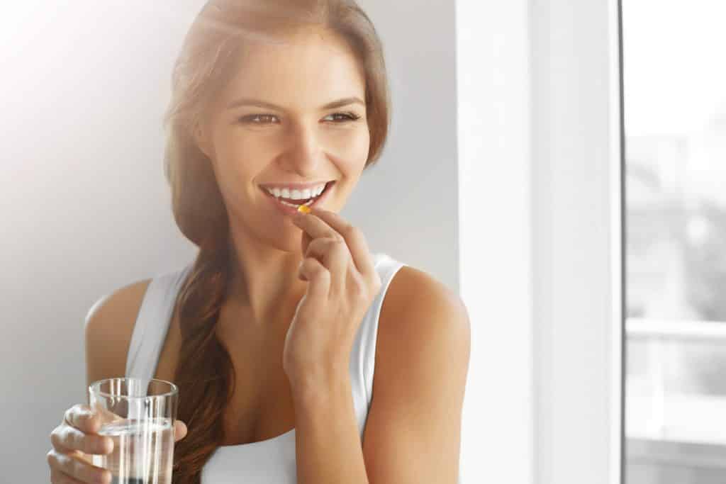 femme qui prend un complement alimentaire avec de l'eau